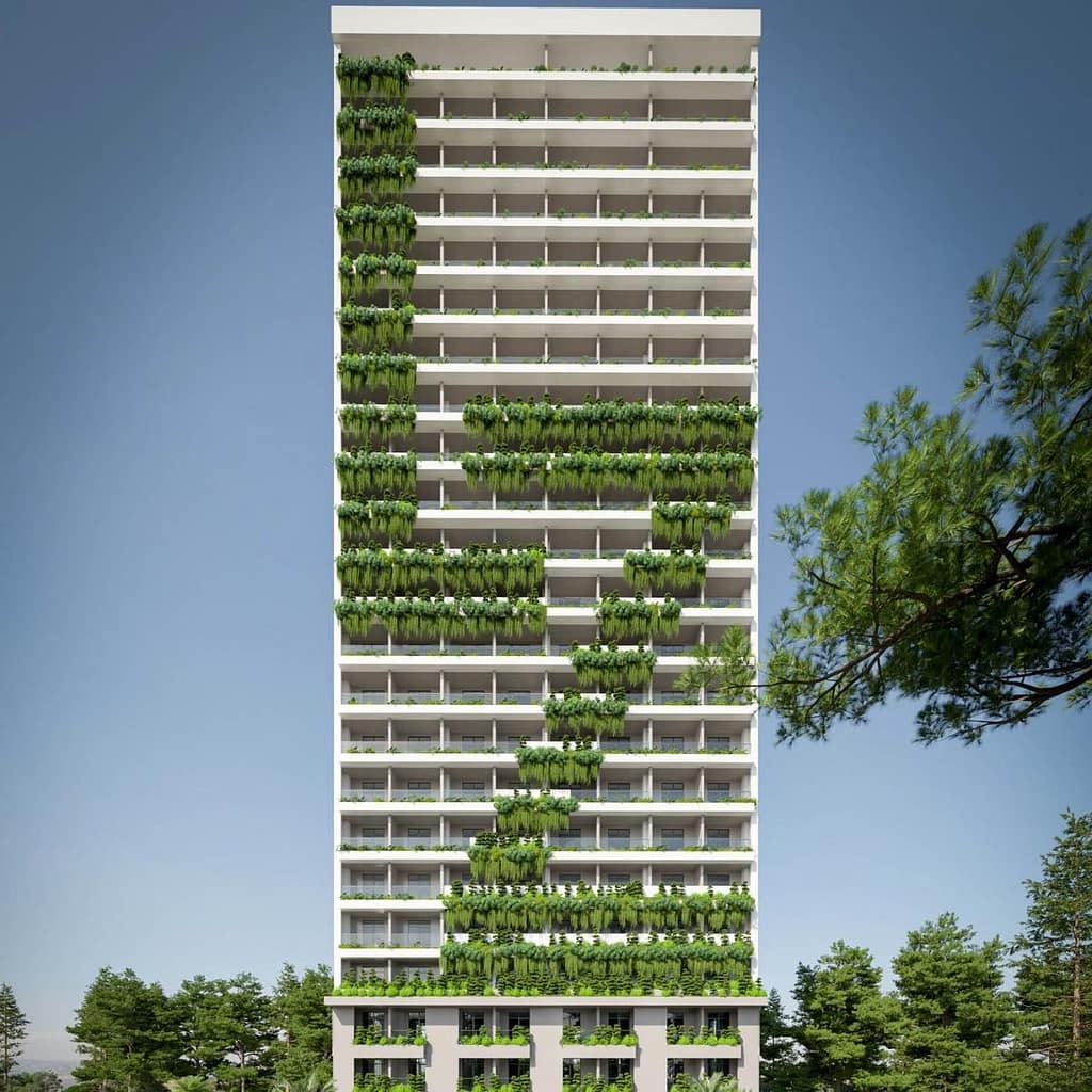 A tall white apartment building with balconies, featuring green plants arranged in a zigzag pattern from the lower left to upper right, against a clear blue sky and surrounded by trees.