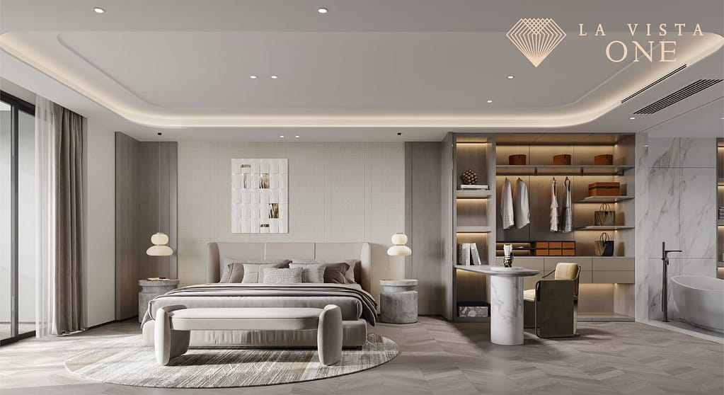 Luxurious modern bedroom with neutral tones, elegant bed, bedside tables with lamps, built-in shelves, a desk area, glass doors, and the La Vista One logo in the top right corner.