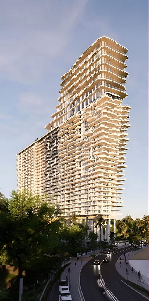 A tall, modern high-rise building with curved balconies and layered architecture stands beside a curved road, surrounded by trees and cars under a clear sky.